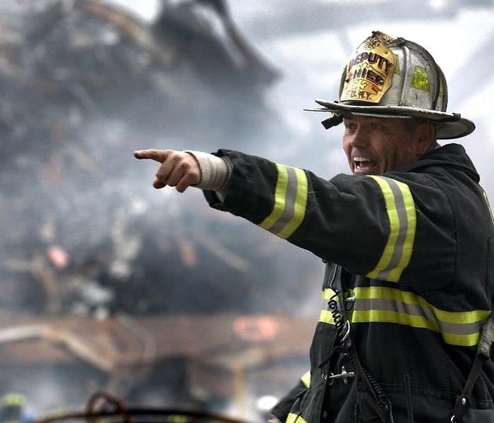 firefighter standing in front of burnt house